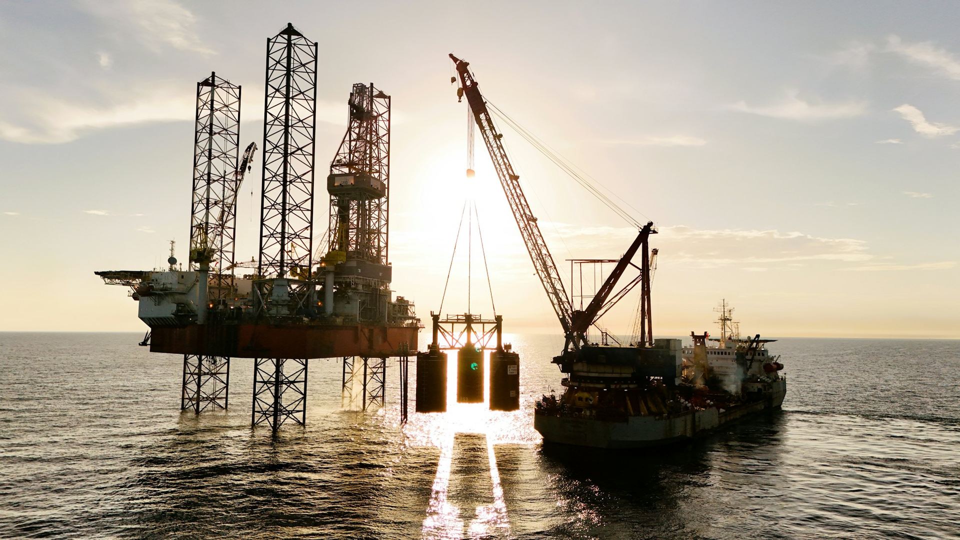 Jack-up drilling rig at sea at sunset